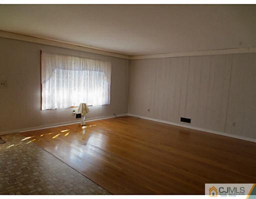 318 New Market Road Dunellen, NJ 08812 - Photo 13 of 23 an empty room with wooden floor and windows