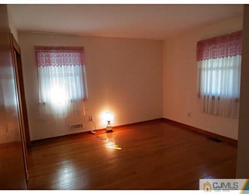 318 New Market Road Dunellen, NJ 08812 - Photo 14 of 23 an empty room with wooden floor and windows