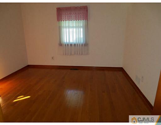 318 New Market Road Dunellen, NJ 08812 - Photo 16 of 23 an empty room with wooden floor and windows