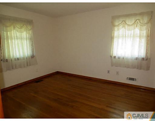 318 New Market Road Dunellen, NJ 08812 - Photo 17 of 23 an empty room with wooden floor and windows