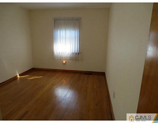 318 New Market Road Dunellen, NJ 08812 - Photo 19 of 23 an empty room with wooden floor and windows