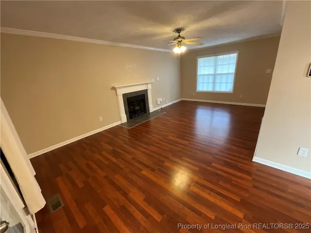 an empty room with wooden floor fireplace and windows