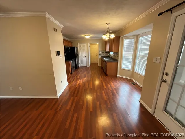 a view of a hallway with wooden floor and a kitchen