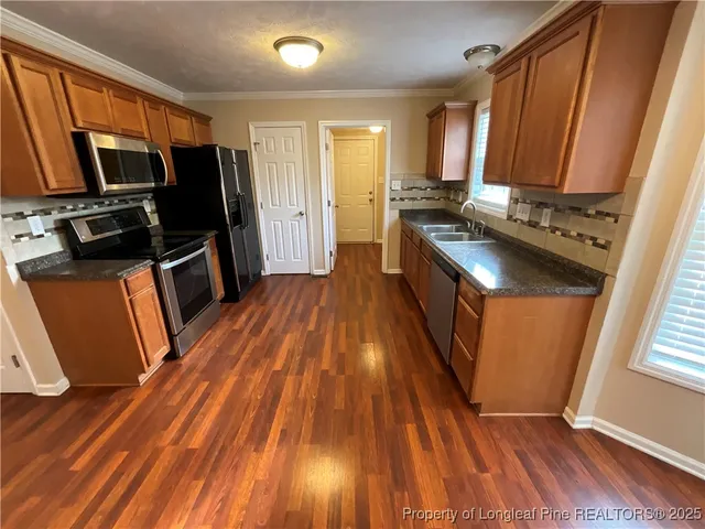a kitchen with wooden floors wooden cabinets a sink and a stove