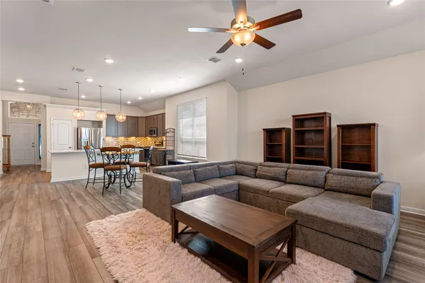a living room with furniture kitchen view and a wooden floor