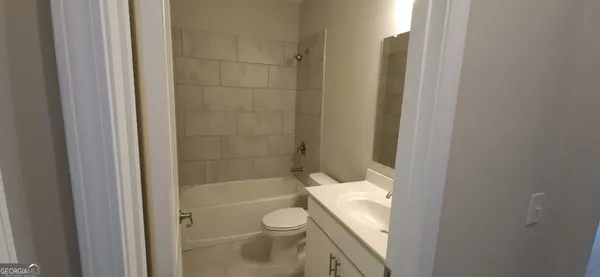 a bathroom with a granite countertop bathtub shower and toilet