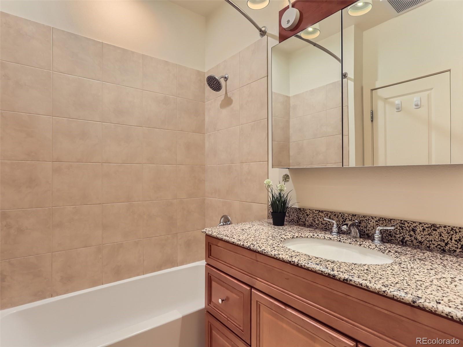 4645 Broadway, Unit B8 Boulder, CO 80304 - Photo 15 of 39 a bathroom with a granite countertop sink a mirror and a bathtub