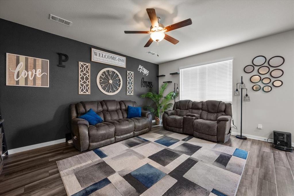 3501 Beutel Road Lorena, TX 76655 - Photo 9 of 33 Living area with wood finished floors, a ceiling fan, and a wood stove