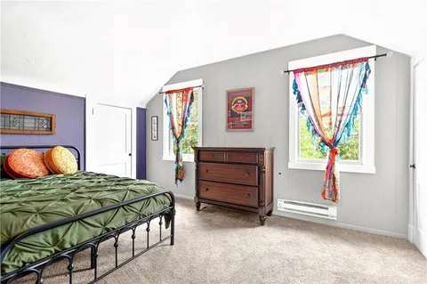 a bedroom with a bed and a dresser next to a window