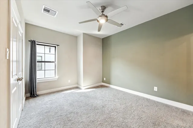 an empty room with windows and ceiling fan