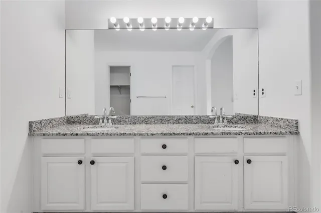 a bathroom with a granite countertop sink and white cabinets