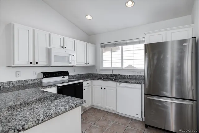 a kitchen with stainless steel appliances granite countertop a refrigerator sink and white cabinets