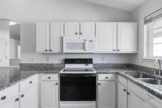 a kitchen with granite countertop white cabinets and white stainless steel appliances