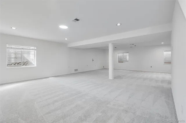 an empty room with a white wall & windows