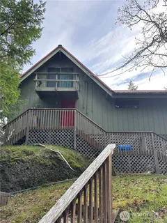 a view of a wooden house with a small yard and wooden fence