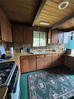 a kitchen with stainless steel appliances granite countertop a sink a stove a refrigerator cabinets and a dining table