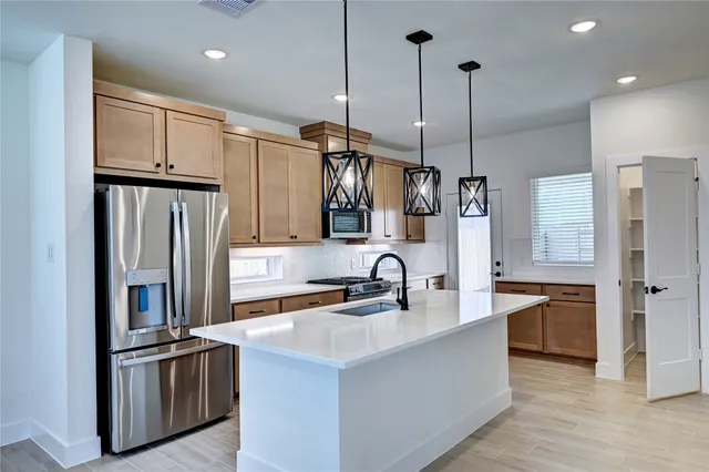 a kitchen with stainless steel appliances granite countertop a sink refrigerator and cabinets