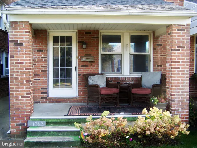 a front view of a house with a chairs and a potted plant