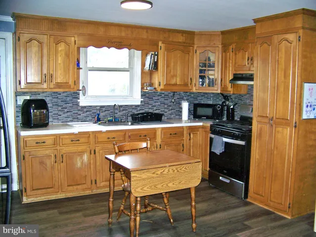 a kitchen with stainless steel appliances granite countertop a stove a sink dishwasher and a refrigerator with wooden floor