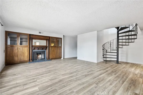 a view of an empty room with wooden floor and stairs