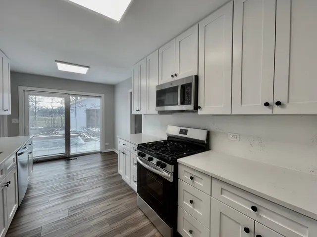a kitchen with stainless steel appliances white cabinets and a stove top oven