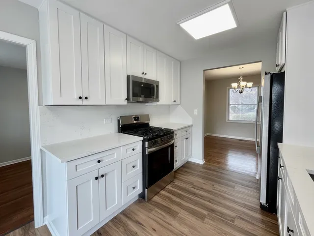 a kitchen with wooden floors and white cabinets