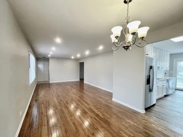 a view of an empty room with wooden floor and a ceiling fan