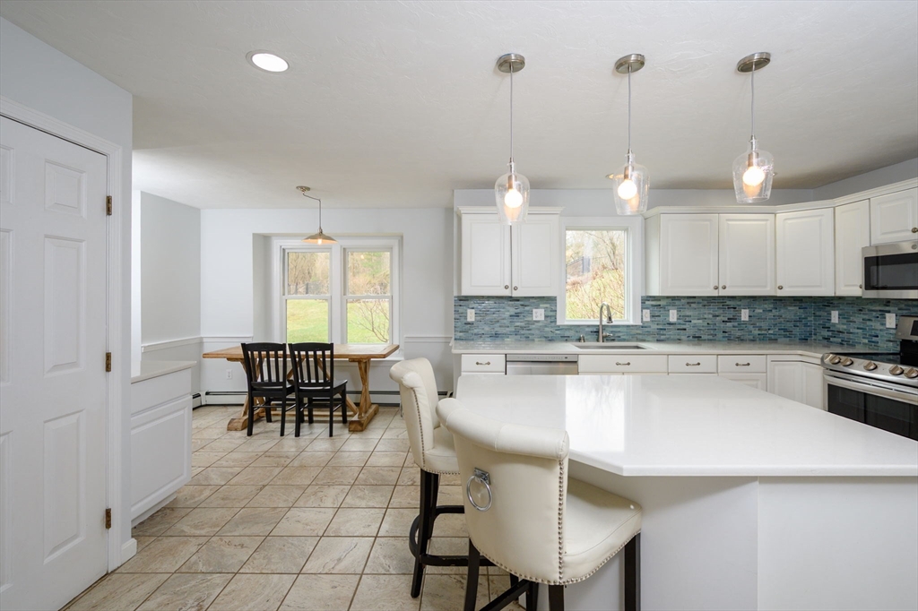 72 Pilgrim Trail Marshfield, MA 02050 - Photo 5 of 42 a kitchen with kitchen island granite countertop a sink a stove a dining table and chairs with wooden floor