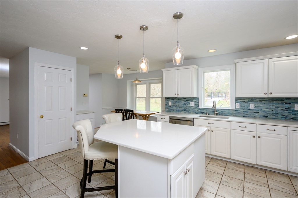72 Pilgrim Trail Marshfield, MA 02050 - Photo 9 of 42 a kitchen with kitchen island granite countertop a table chairs sink and cabinets