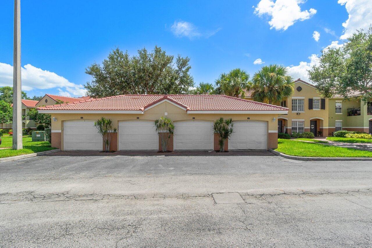 10306 Fox Trail Road South, Unit 906 West Palm Beach, FL 33411 - Photo 20 of 26 a front view of a house with a yard and garage