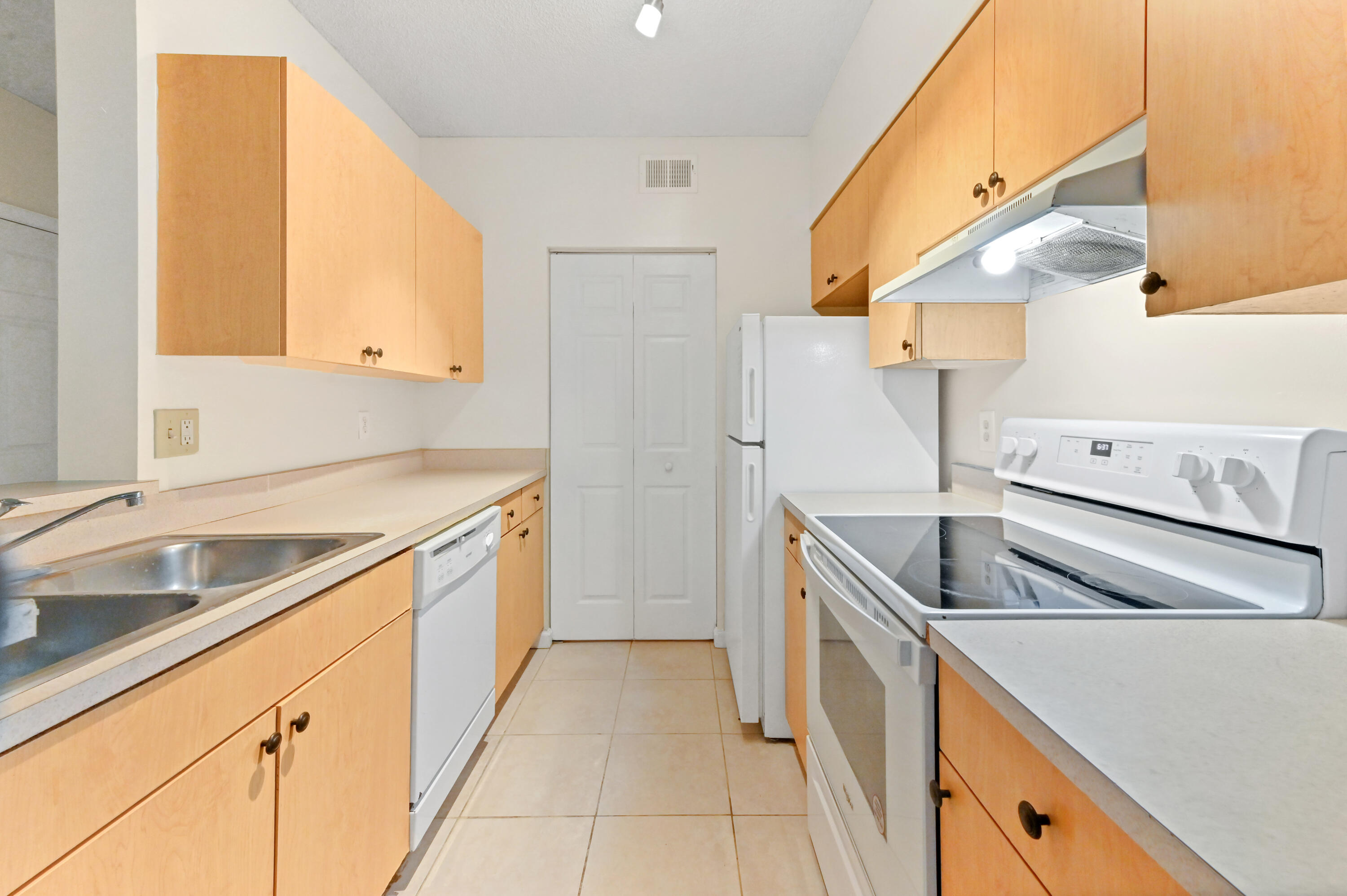 10306 Fox Trail Road South, Unit 906 West Palm Beach, FL 33411 - Photo 9 of 26 a kitchen with a sink and a refrigerator
