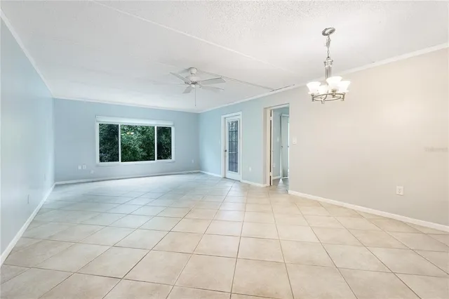 a view of a livingroom with a chandelier fan and windows