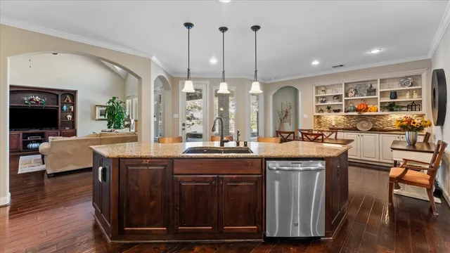 a kitchen with stainless steel appliances granite countertop a sink a stove and a wooden floors