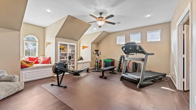 a living room with furniture gym equipment and a ceiling fan