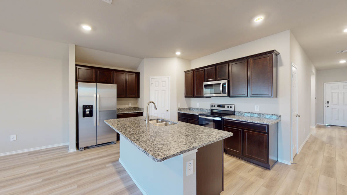 575 Hector Loop Georgetown, TX 78626 - Photo 5 of 28 Kitchen featuring a central island with a double basin sink, dark wood cabinetry, stainless steel appliances, granite countertops, and light wood-finish flooring
