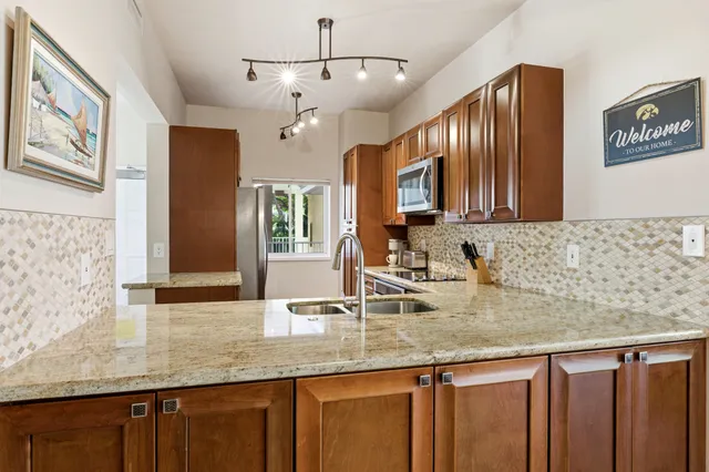a kitchen with granite countertop stainless steel appliances sink and microwave