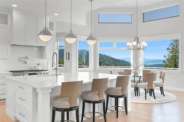 a open kitchen with stainless steel appliances granite countertop a dining table chairs and white cabinets
