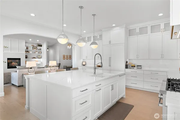 a large white kitchen with a white cabinets and chandelier