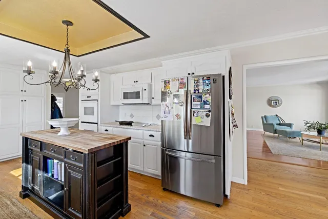 a kitchen with stainless steel appliances granite countertop a refrigerator a stove and a chandelier
