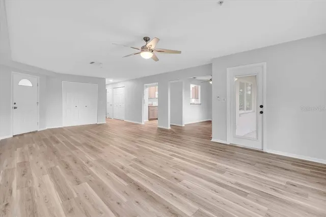 a view of empty room with wooden floor and ceiling fan