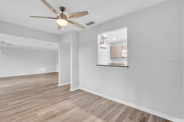 an empty room with wooden floor and a ceiling fan