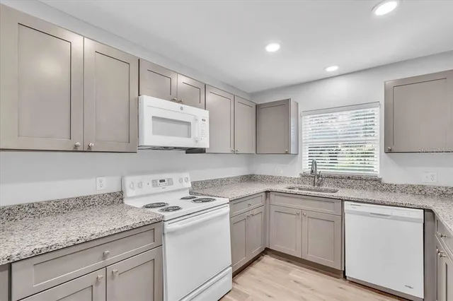 a kitchen with granite countertop white cabinets white appliances and a sink