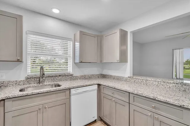 a kitchen with granite countertop cabinets sink and window
