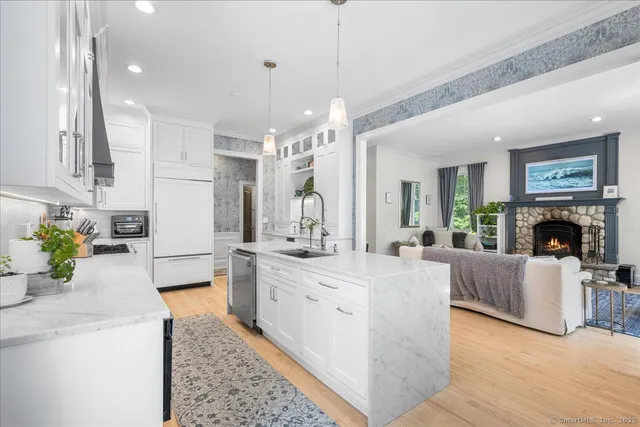 a large white kitchen with a large window a oven and stainless steel appliances
