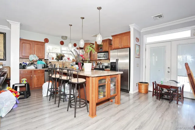 a kitchen with stainless steel appliances kitchen island granite countertop a table chairs and a wooden floor