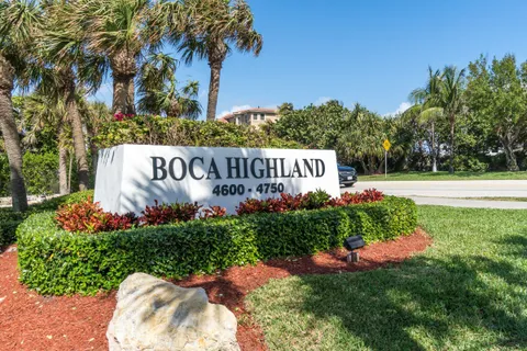 a front view of a multi story residential apartment building with yard and parking