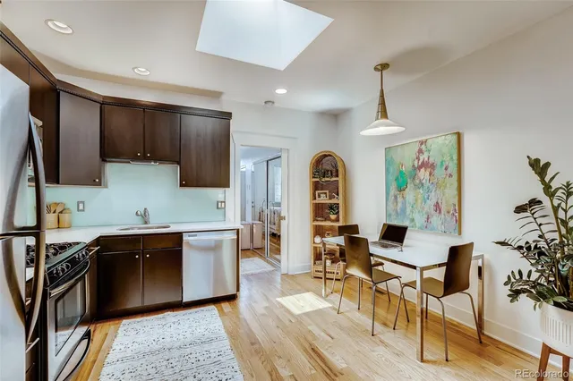 a kitchen with stainless steel appliances granite countertop a refrigerator a sink dishwasher a dining table and chairs with wooden floor