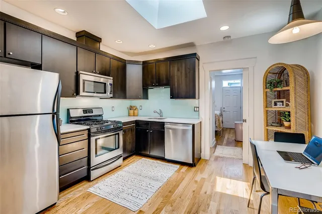 a kitchen with stainless steel appliances granite countertop a refrigerator a stove top oven a sink dishwasher and white cabinets with wooden floor