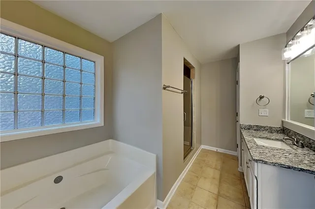 a bathroom with a granite countertop sink and a bathtub