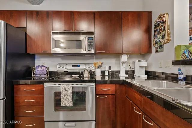 a kitchen with stainless steel appliances granite countertop a sink a stove and a refrigerator